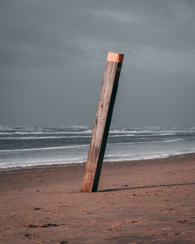 Lonely wooden pole standing on a deserted beach under a cloudy sky, Bergen aan Zee.