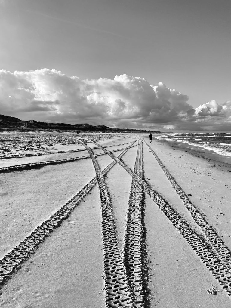 Black and white beach scene at Bergen aan Zee with dramatic clouds.